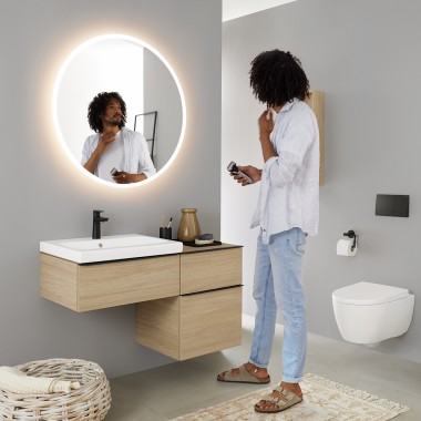 Homme se regardant dans un miroir rond lumineux Geberit Option