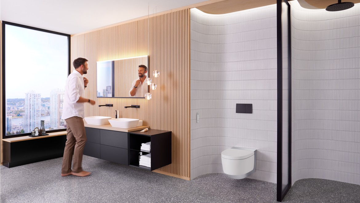 Man in badkamer staand voor Geberit Option Plus Square spiegel en zwart Geberit ONE badkamermeubilair (© Geberit)