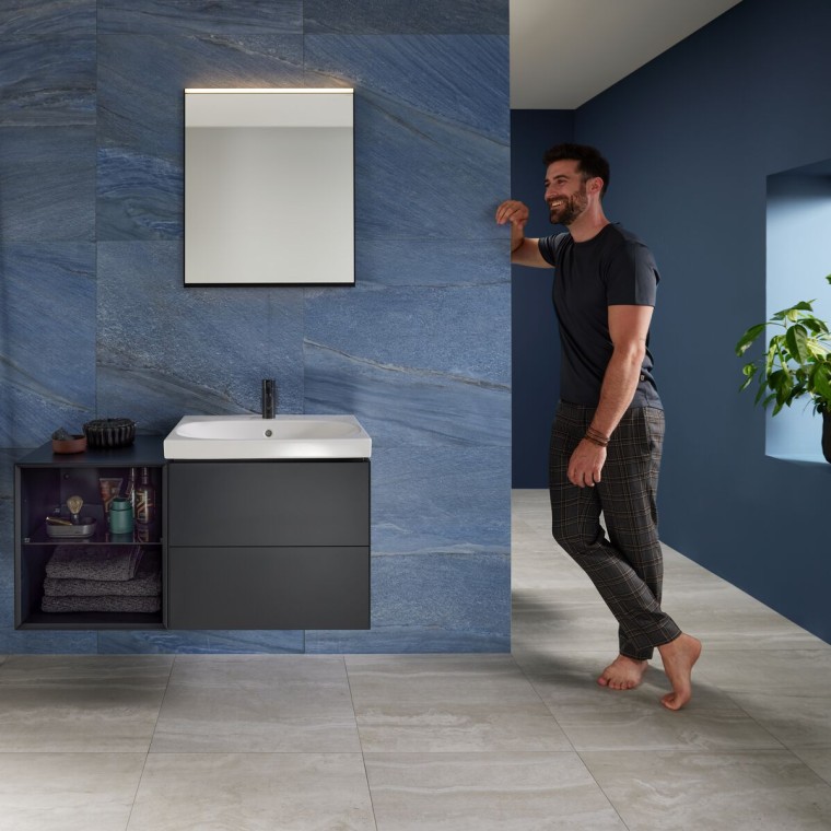 Man leunt tegen muur in blauwe badkamer met Geberit Mix & Match wastafelruimte Man leunt tegen muur in blauwe badkamer met Geberit Mix & Match wastafelruimte