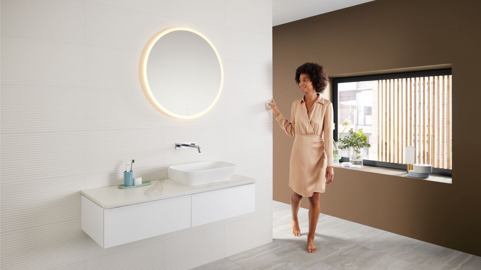 Femme dans une salle de bains moderne avec une palette de nuances brunes – la dernière tendance dans la salle de bains – et un espace lavabo Mix & Match Femme dans une salle de bains moderne avec une palette de nuances brunes – la dernière tendance dans la salle de bains – et un espace lavabo Mix & Match