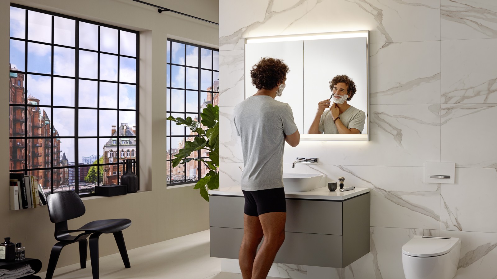 Homme se rasant au lavabo avec meuble et armoire de toilette Geberit ONE Homme se rasant au lavabo avec meuble et armoire de toilette Geberit ONE