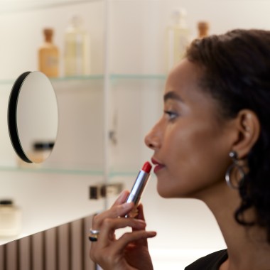 Vrouw die make-up aanbrengt voor de spiegel