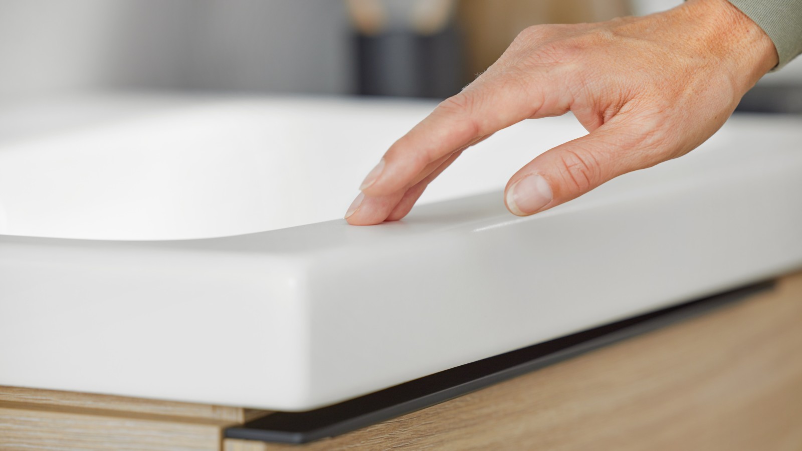 Image macro d'une main touchant un lavabo Geberit iCon en blanc mat Image macro d'une main touchant un lavabo Geberit iCon en blanc mat