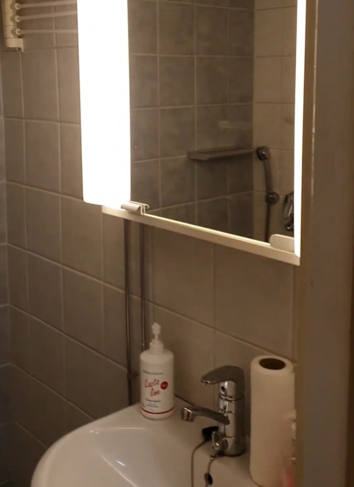 Een foto vóór de renovatie van de kleine badkamer met spiegelkast en wasbak (© Meja Hynynen)