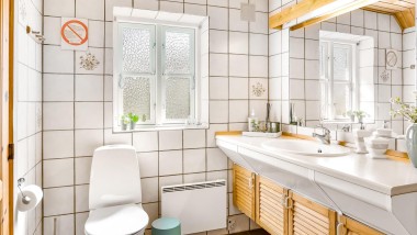 La salle de bains d'origine avec WC au sol, carrelage blanc et meubles de salle de bains en bois (© @triner2 et @strandparken3)