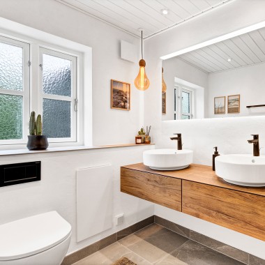 Salle de bains rénovée et lumineuse avec deux lavabos ronds, un grand miroir et des meubles de salle de bains en bois (© @triner2 et @strandparken3)
