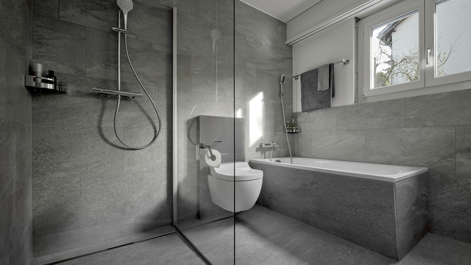 Un WC-douche entre une douche de plain-pied et une baignoire Un WC-douche entre une douche de plain-pied et une baignoire