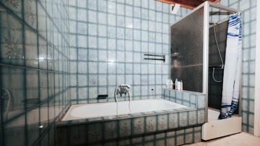 Badkamer met blauwe tegels, douchecabine en bad