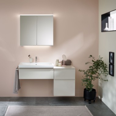 Zone de lavage avec meubles de salle de bains, lavabo et armoire à miroir Geberit devant un mur aux tons pastel