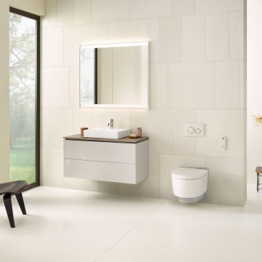 Salle de bains beige avec armoire de toilette, meuble sous lavabo, plaque de déclenchement et céramiques sanitaires de Geberit