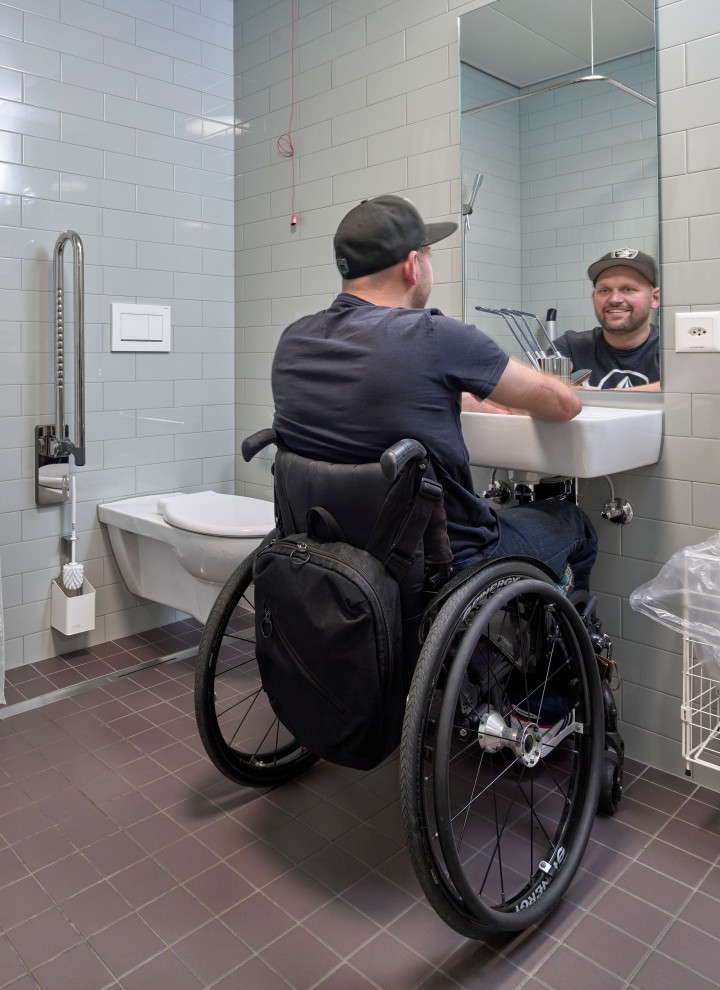 Peter Roos en fauteuil roulant au niveau de la zone de lavage dans une salle de bains adaptée aux PMR (© Ben Huggler) Peter Roos en fauteuil roulant au niveau de la zone de lavage dans une salle de bains adaptée aux PMR (© Ben Huggler)