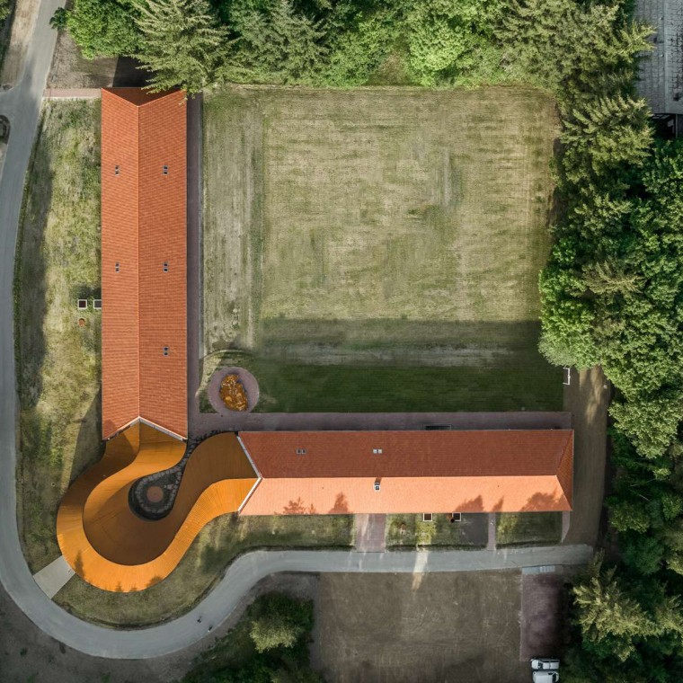Het bovenaanzicht toont het nieuwe, ronde gebouw dat de twee historische gebouwen met de dakpannen verbindt (© R_Hjortshoj) Het bovenaanzicht toont het nieuwe, ronde gebouw dat de twee historische gebouwen met de dakpannen verbindt (© R_Hjortshoj)