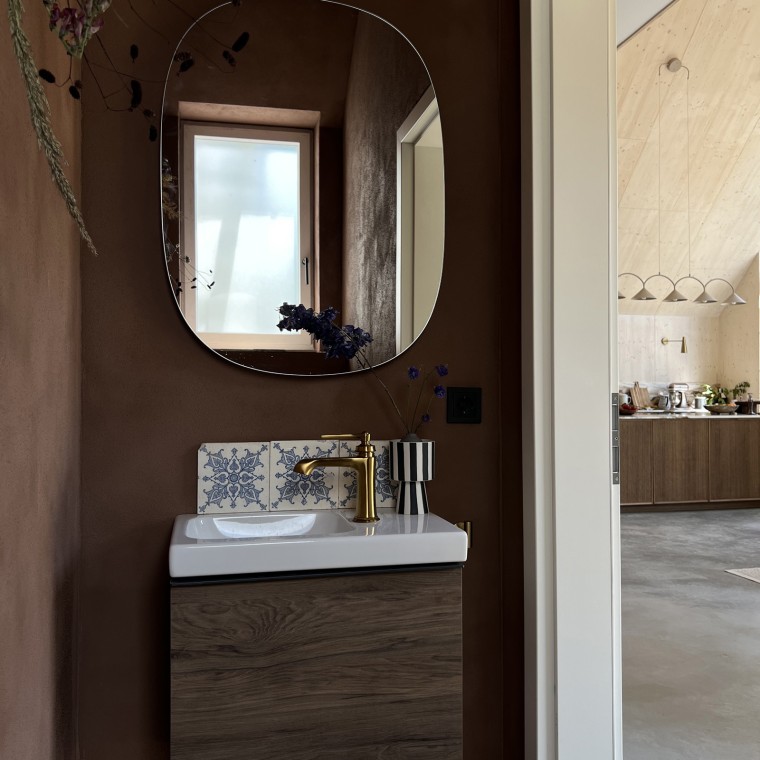 Le bois est un élément décoratif présent dans toute la maison. Le meuble sous lavabo Geberit iCon en noyer hickory relie les pièces avec élégance (© Büşra Qadir)