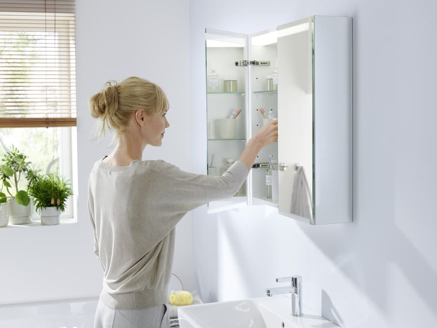 Spiegelkast met licht van Geberit Option met een vrouw Spiegelkast met licht van Geberit Option met een vrouw
