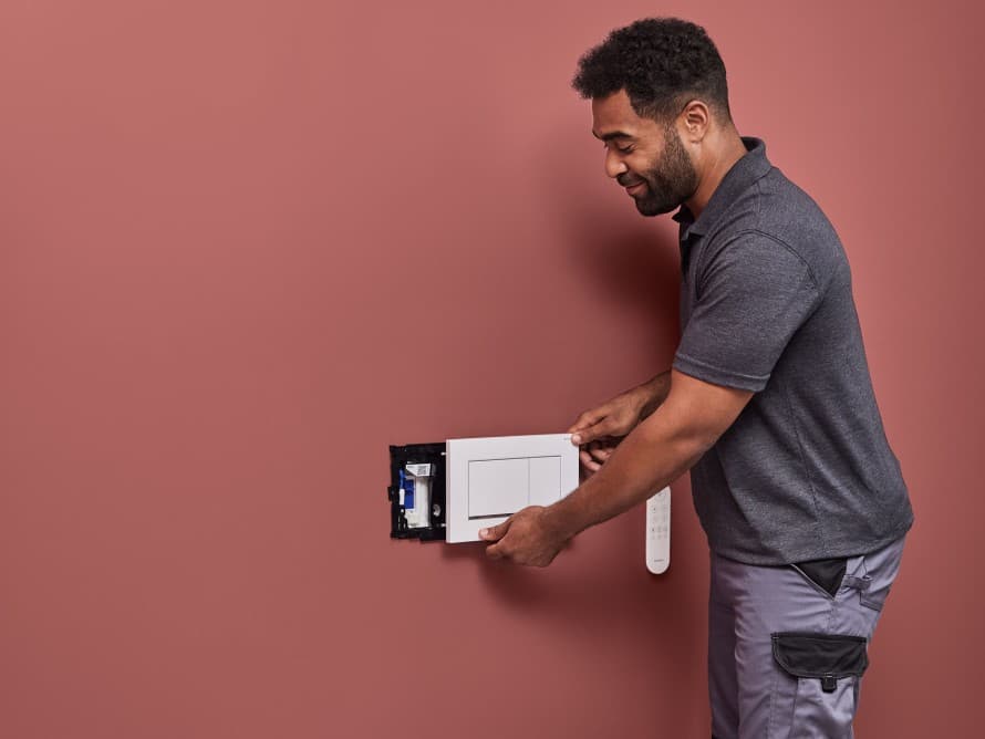 Un homme installe le système d'extraction des odeurs Geberit DuoFresh Un homme installe le système d'extraction des odeurs Geberit DuoFresh