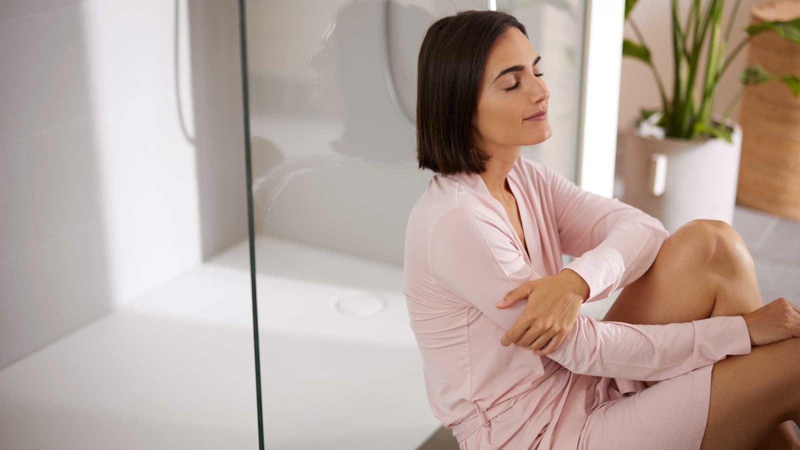 Femme assise dans la salle de bains, devant la douche Femme assise dans la salle de bains, devant la douche